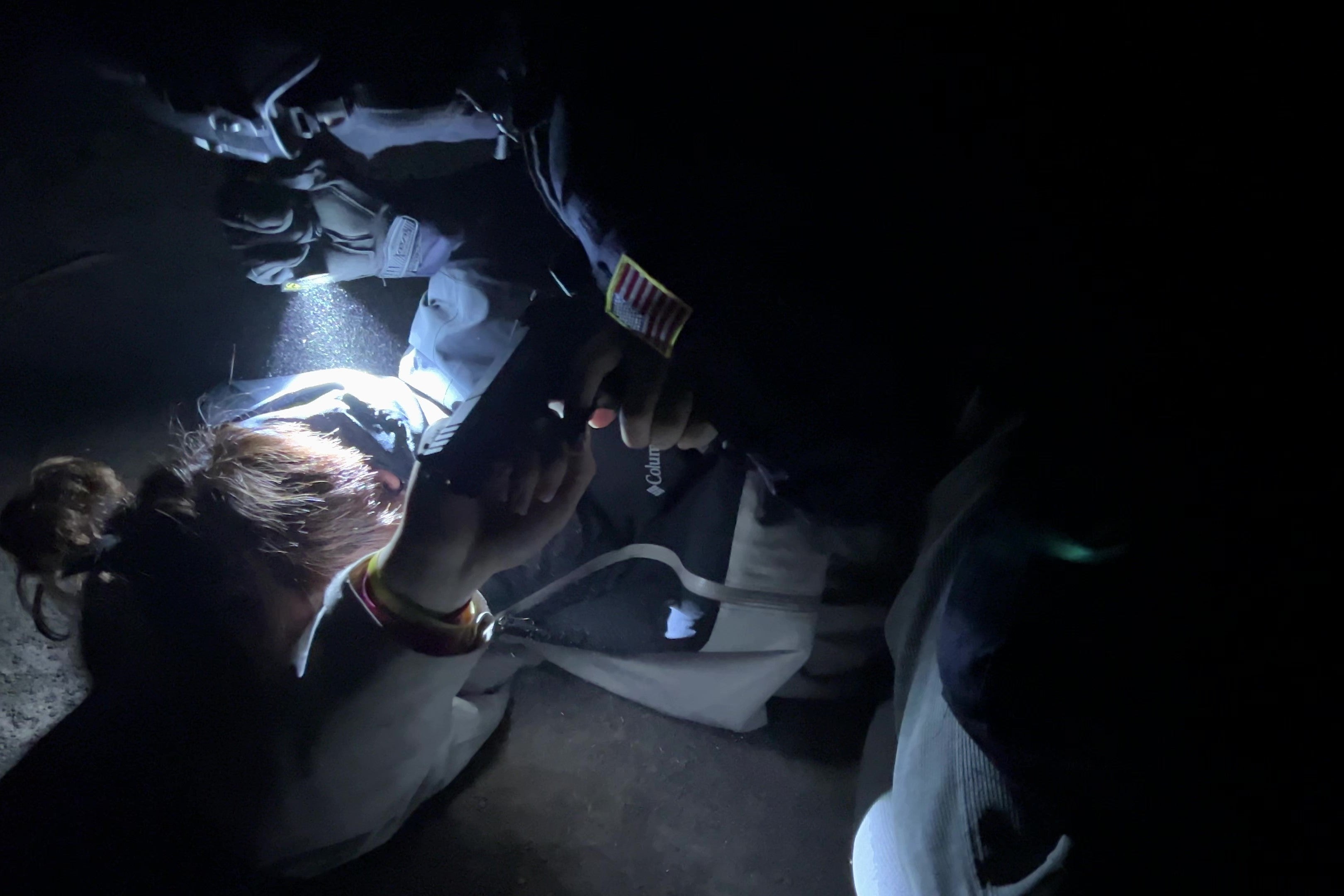 Hiker with headlamp gazing at starry night sky over rugged mountain peaks