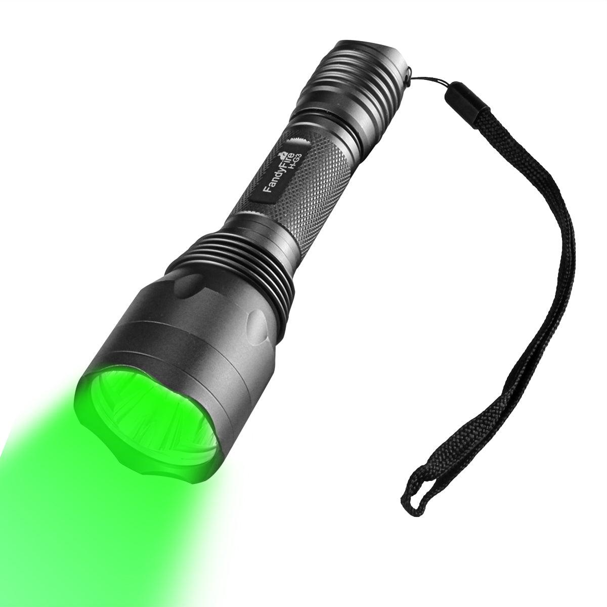 Black tactical flashlight emitting bright green light with wrist strap, isolated on white background